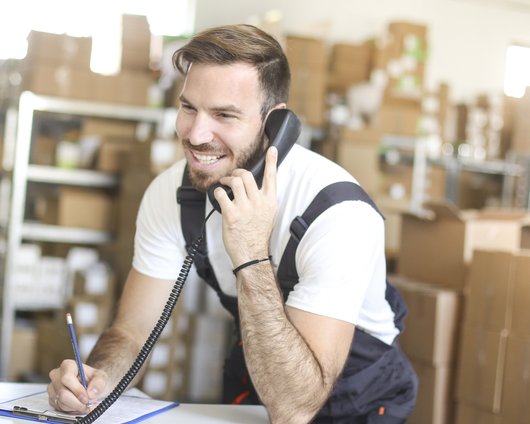 iStock - Jan 2021 - man on phone in warehouse - medium business - parcel - packing