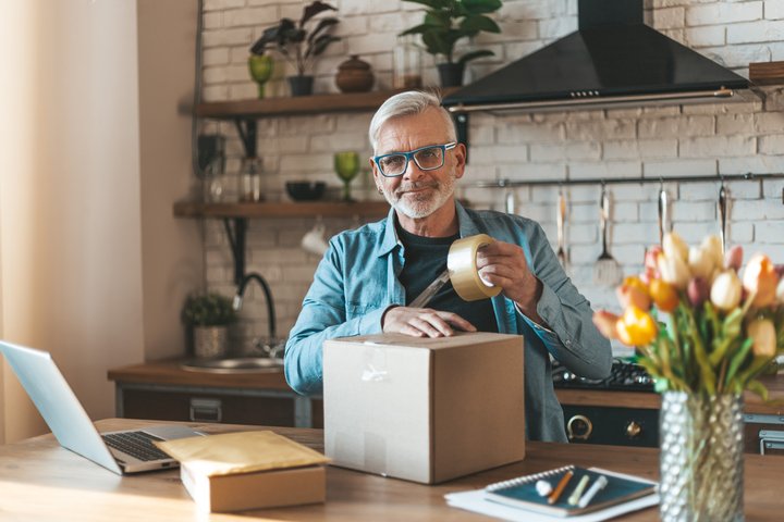 Old man taping a parcel